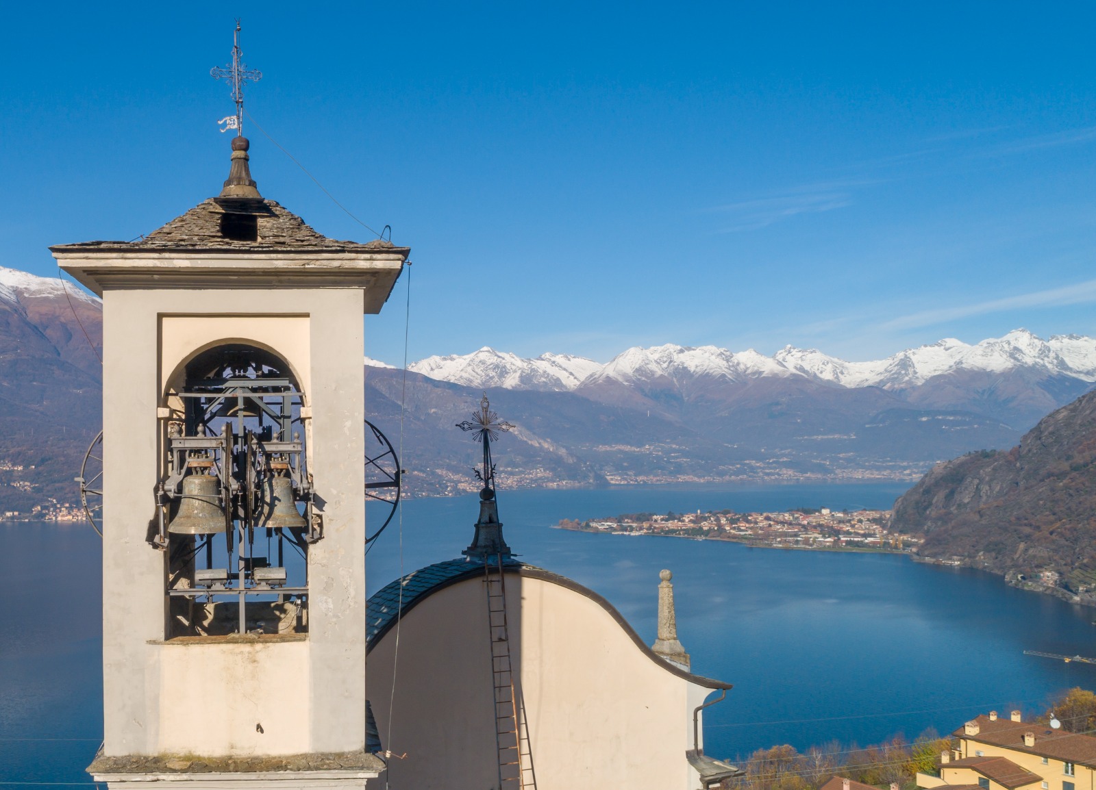 Campanile del santuario di Lezzeno con il lago e le montagne innevate sullo sfondo